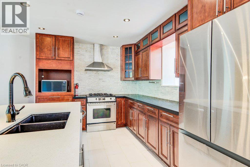Kitchen featuring wood cabinetry, stainless steel appliances, a white solid surface countertop, and a black double basin sink - 109 White Oak Place, Waterloo, ON - Indoor Photo Showing Kitchen With Double Sink