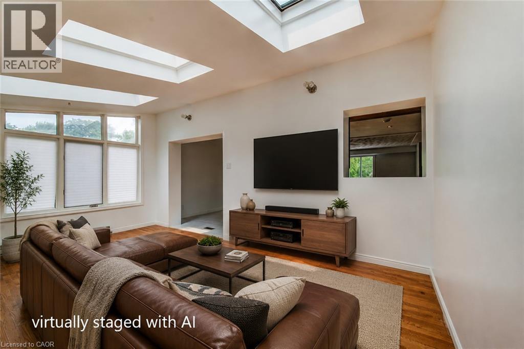 Living area featuring multiple skylights, large multi-pane windows with blinds, and wood-finish flooring - 109 White Oak Place, Waterloo, ON - Indoor