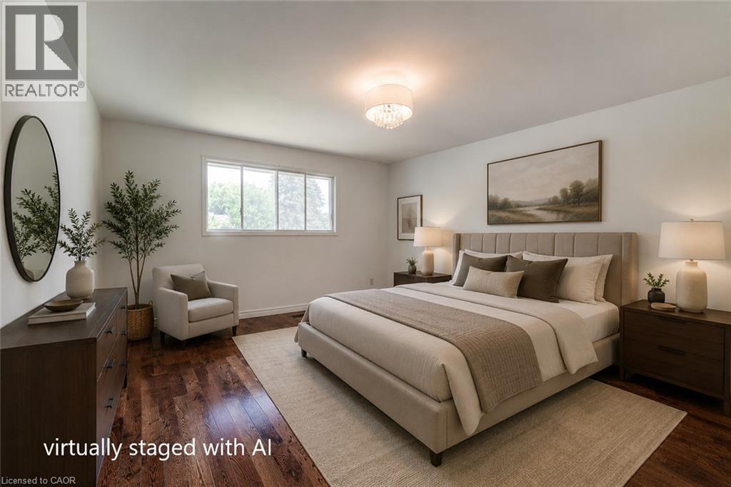 Spacious bedroom featuring rich wood-finish flooring, a contemporary semi-flush mount light fixture, and a wide window offering natural light - 109 White Oak Place, Waterloo, ON - Indoor Photo Showing Bedroom