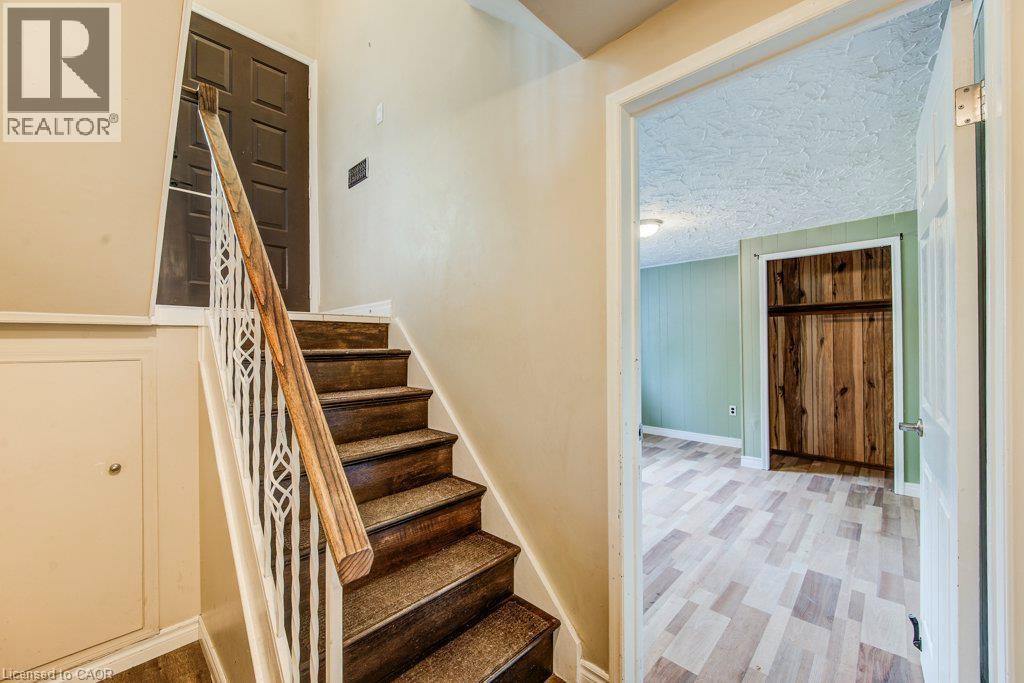 Staircase featuring wood steps with carpet treads, a white decorative metal railing, and a wood handrail - 109 White Oak Place, Waterloo, ON - Indoor Photo Showing Other Room
