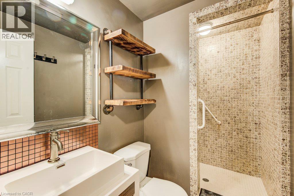Bathroom featuring a walk-in shower with mosaic tile, custom wood shelving, a contemporary vanity with an integrated sink, a rectangular mirror, and a copper tile backsplash - 109 White Oak Place, Waterloo, ON - Indoor Photo Showing Bathroom