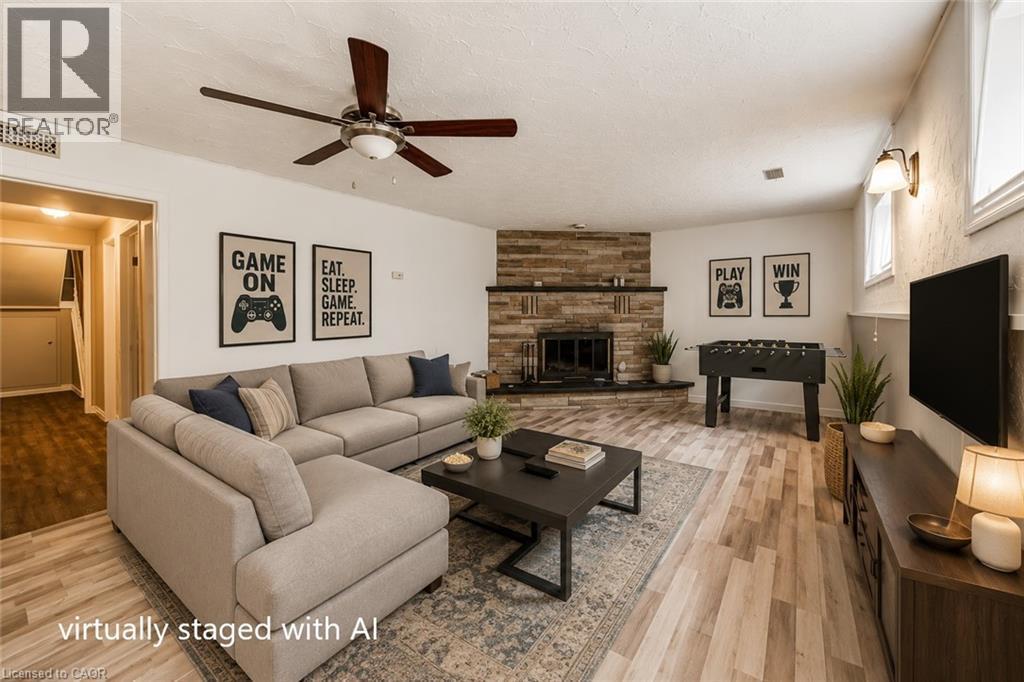 Spacious room featuring wood-finish flooring, a ceiling fan, and a prominent fireplace with a stone surround - 109 White Oak Place, Waterloo, ON - Indoor Photo Showing Living Room With Fireplace