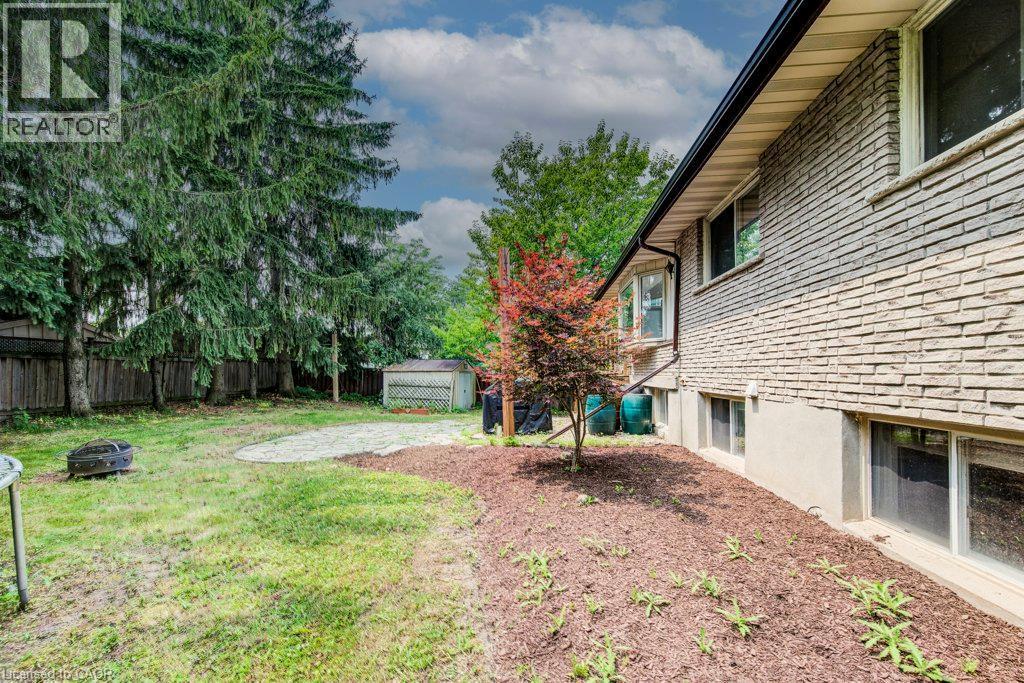 Expansive backyard featuring a manicured lawn, established privacy fencing, and mature evergreen trees - 109 White Oak Place, Waterloo, ON - Outdoor