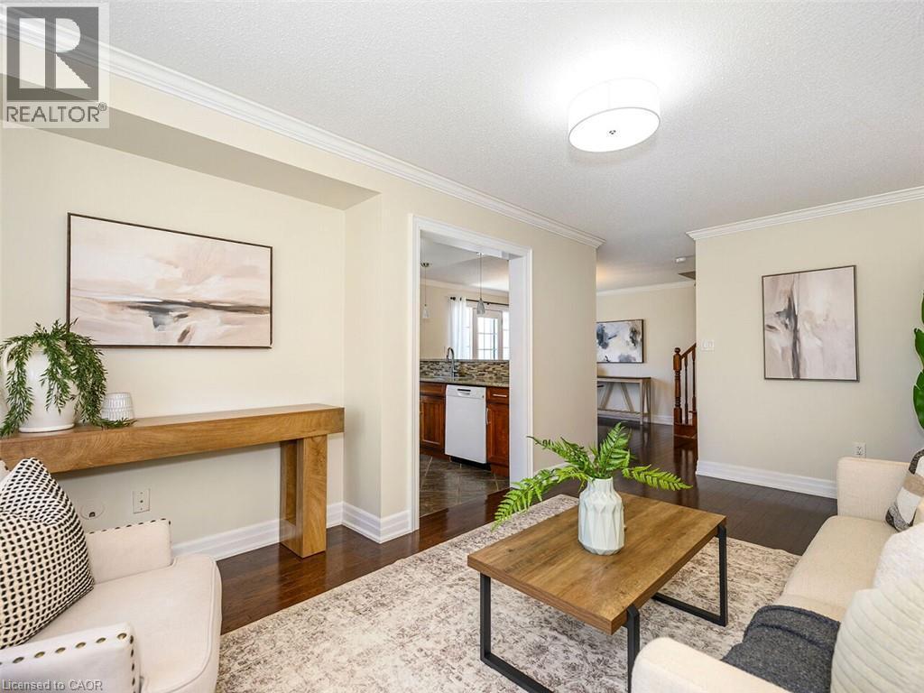 Living area featuring dark wood-finish flooring, light-toned walls, and white crown molding - 656 Frank Place, Milton, ON - Indoor Photo Showing Living Room