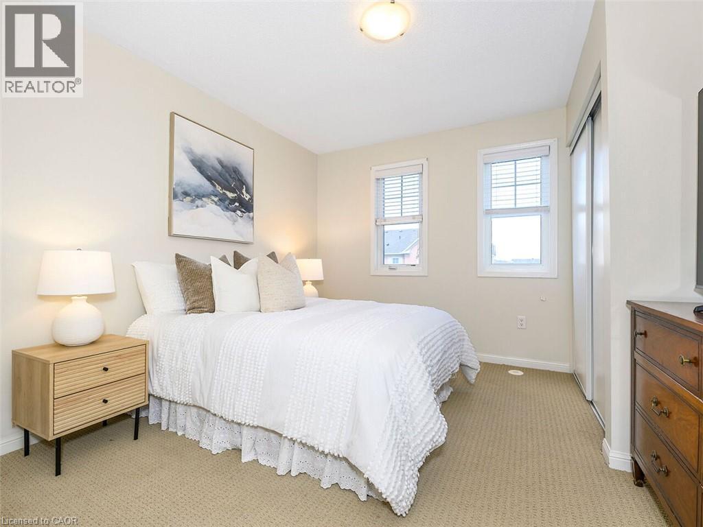 Carpeted bedroom featuring two windows with horizontal blinds, a flush-mount ceiling light, and a built-in sliding closet - 656 Frank Place, Milton, ON - Indoor Photo Showing Bedroom