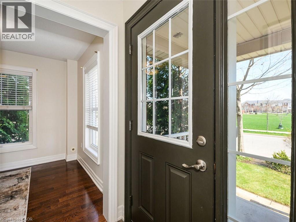 Entryway featuring a dark paneled door with glass inserts, wood-finish flooring, and white trim - 656 Frank Place, Milton, ON - Indoor Photo Showing Other Room