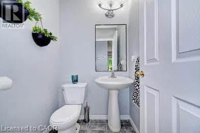 Pedestal sink and toilet with paneled door and overhead lighting - 175 David Bergey Drive Unit# L74, Kitchener, ON - Indoor Photo Showing Bathroom