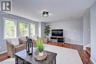 Living area featuring rich wood-finish flooring, light gray wall tones, and abundant natural light from multiple windows - 175 David Bergey Drive Unit# L74, Kitchener, ON - Indoor Photo Showing Living Room