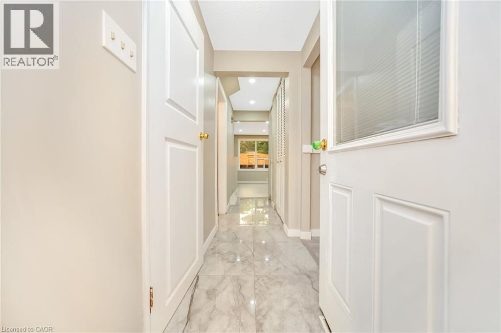 Hallway featuring polished tile flooring, recessed lighting, white paneled doors, and a partial glass door with integrated blinds - 53 Burns Drive, Guelph, ON - Indoor Photo Showing Other Room