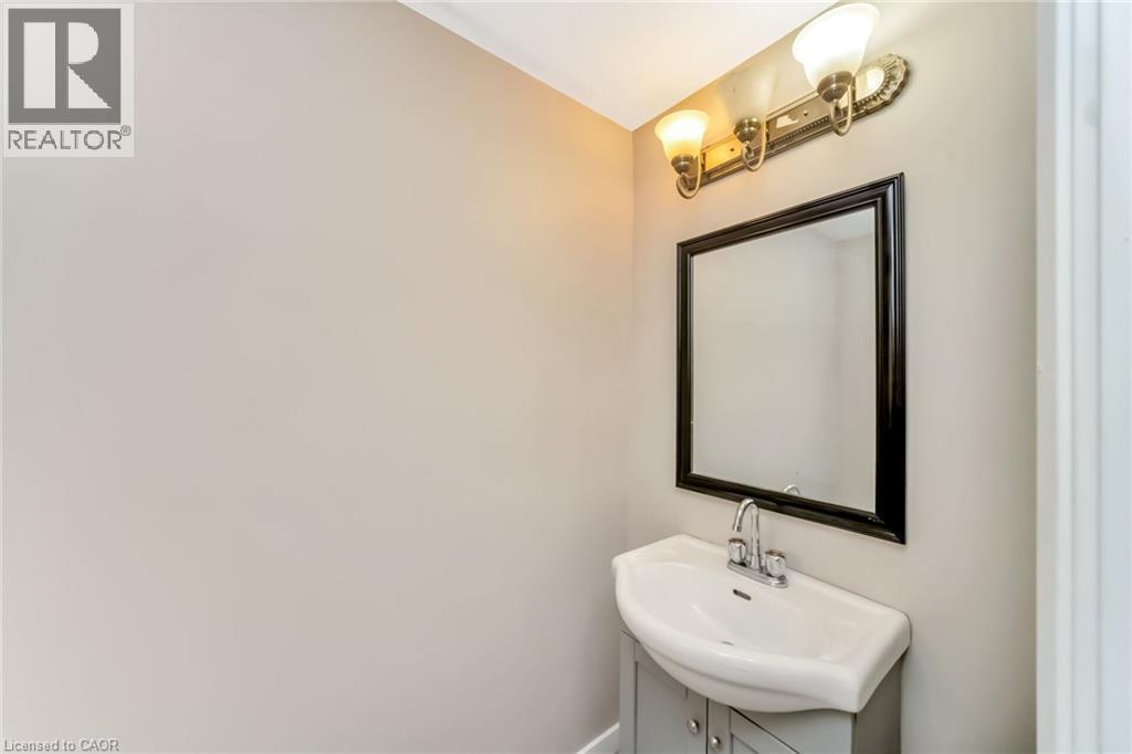 Pedestal sink vanity with a chrome faucet, framed mirror, and dual-bulb light fixture - 53 Burns Drive, Guelph, ON - Indoor Photo Showing Bathroom
