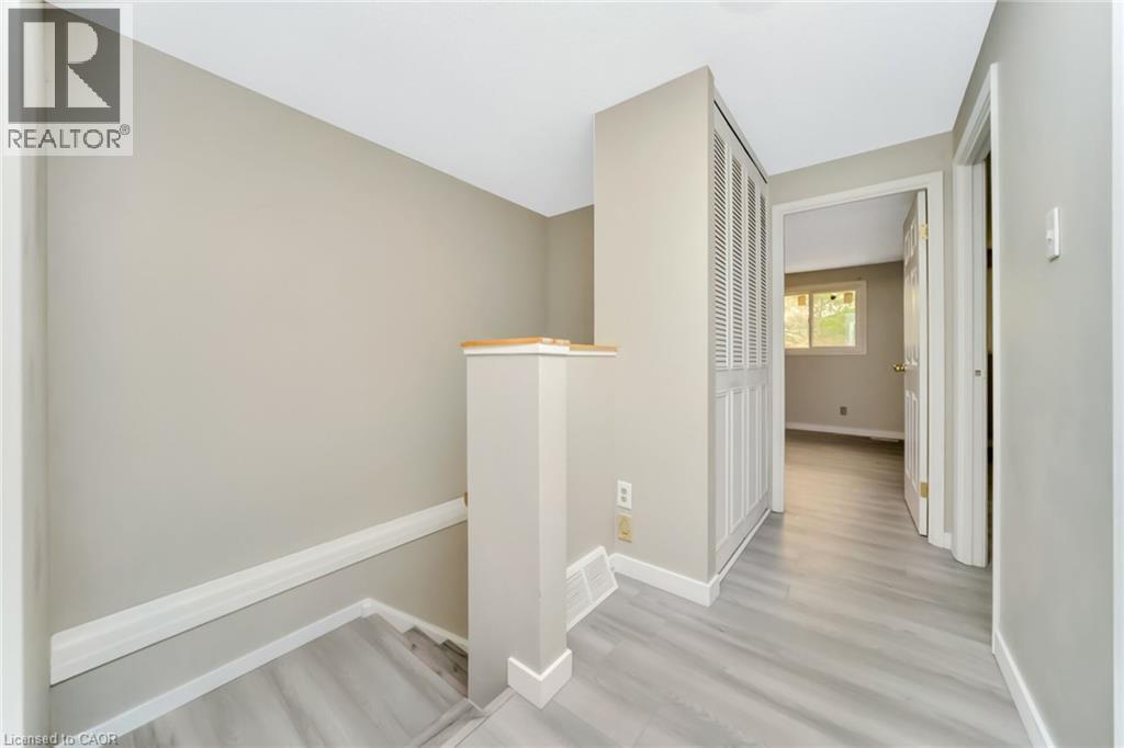 Upper-level hallway featuring light wood-finish flooring, a built-in louvered closet, and neutral wall paint - 53 Burns Drive, Guelph, ON - Indoor Photo Showing Other Room