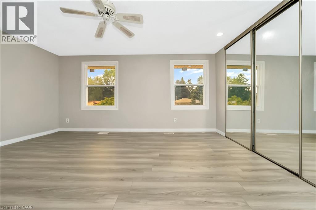 Spacious room featuring wood-finish flooring, light grey walls, and a white ceiling with a ceiling fan - 53 Burns Drive, Guelph, ON - Indoor Photo Showing Other Room