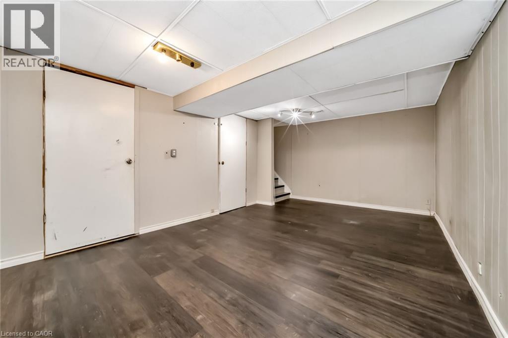 Spacious room featuring dark wood-finish flooring, light neutral-toned walls, and a drop-tile ceiling with recessed lighting - 53 Burns Drive, Guelph, ON - Indoor