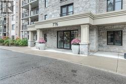Stone-clad building facade featuring a prominent entrance with double glass doors, a decorative overhang, and architectural columns -
