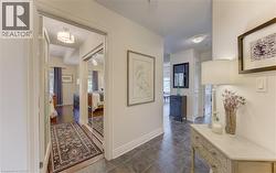 Hallway featuring dark tile flooring, white baseboards, and a doorway opening to a room with wood-finish flooring and mirrored closet doors -