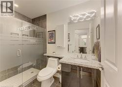 Contemporary bathroom featuring a frameless glass shower enclosure with frosted privacy bands, a white shower pan, and dark large-format tile walls -
