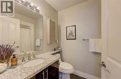 Bathroom featuring a stone-finish countertop with an integrated sink, satin nickel faucet, and dark wood-finish vanity cabinetry -
