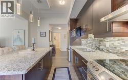Kitchen featuring dark wood-finish cabinetry, light speckled countertops, and stainless steel appliances -