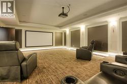 Dedicated media room featuring a large projection screen, recessed ceiling projector, and integrated baseboard lighting -