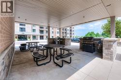 Covered outdoor patio featuring multiple picnic tables and built-in grilling stations with stone facades -