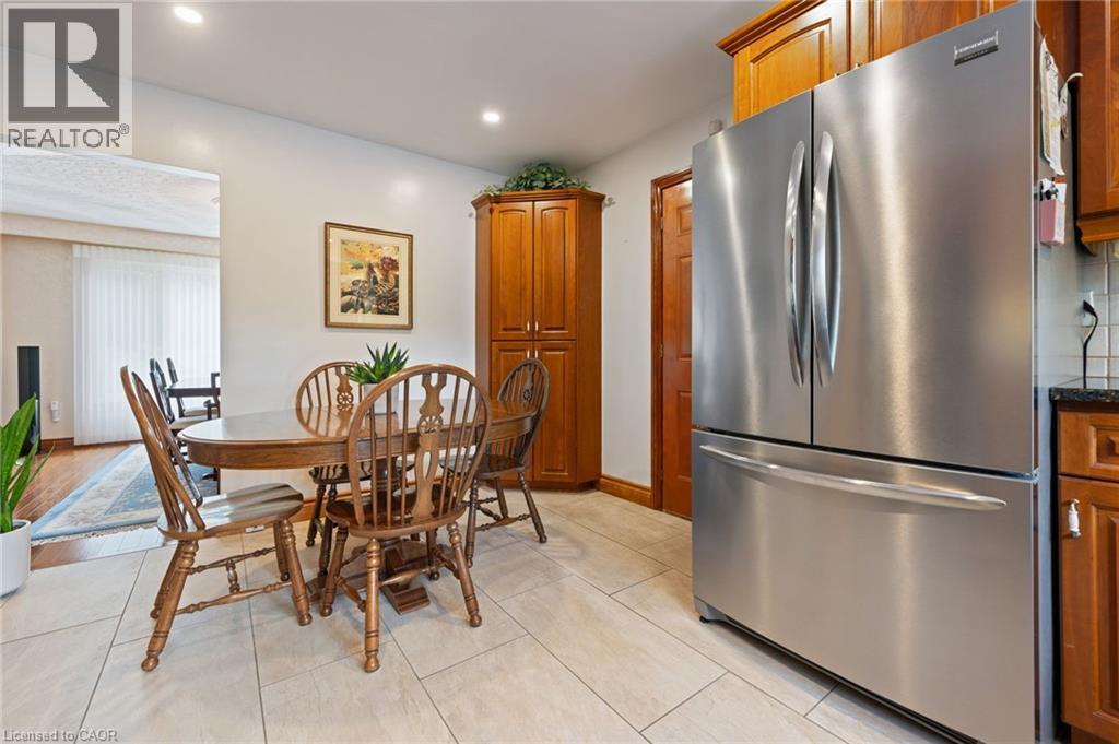 Kitchen area featuring large format tile flooring, recessed lighting, stainless steel French door refrigerator, and wood cabinetry - 7 Thomson Road, Simcoe, ON - Indoor Photo Showing Dining Room