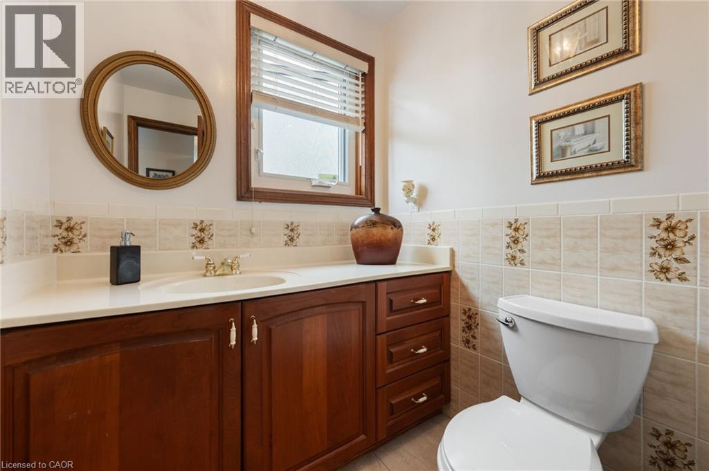 Bathroom featuring a wood-finish vanity with a built-in sink, a light-toned countertop, and a window with blinds - 7 Thomson Road, Simcoe, ON - Indoor Photo Showing Bathroom