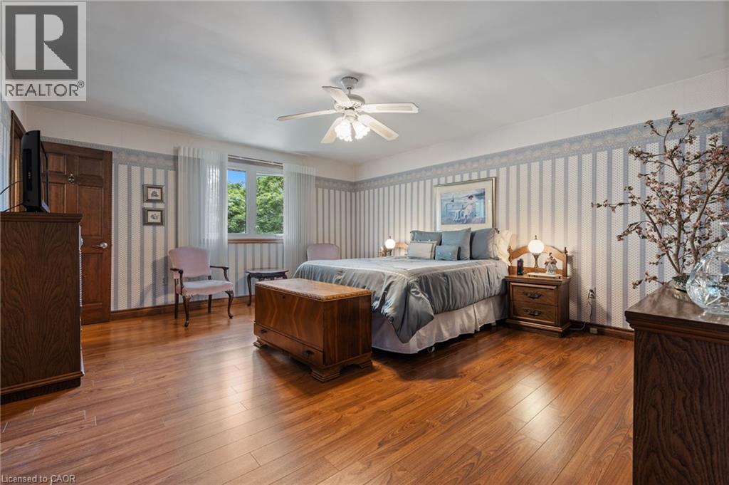 Bedroom featuring wood-finish flooring, a ceiling fan with light fixture, and a window with sheer curtains - 7 Thomson Road, Simcoe, ON - Indoor Photo Showing Bedroom
