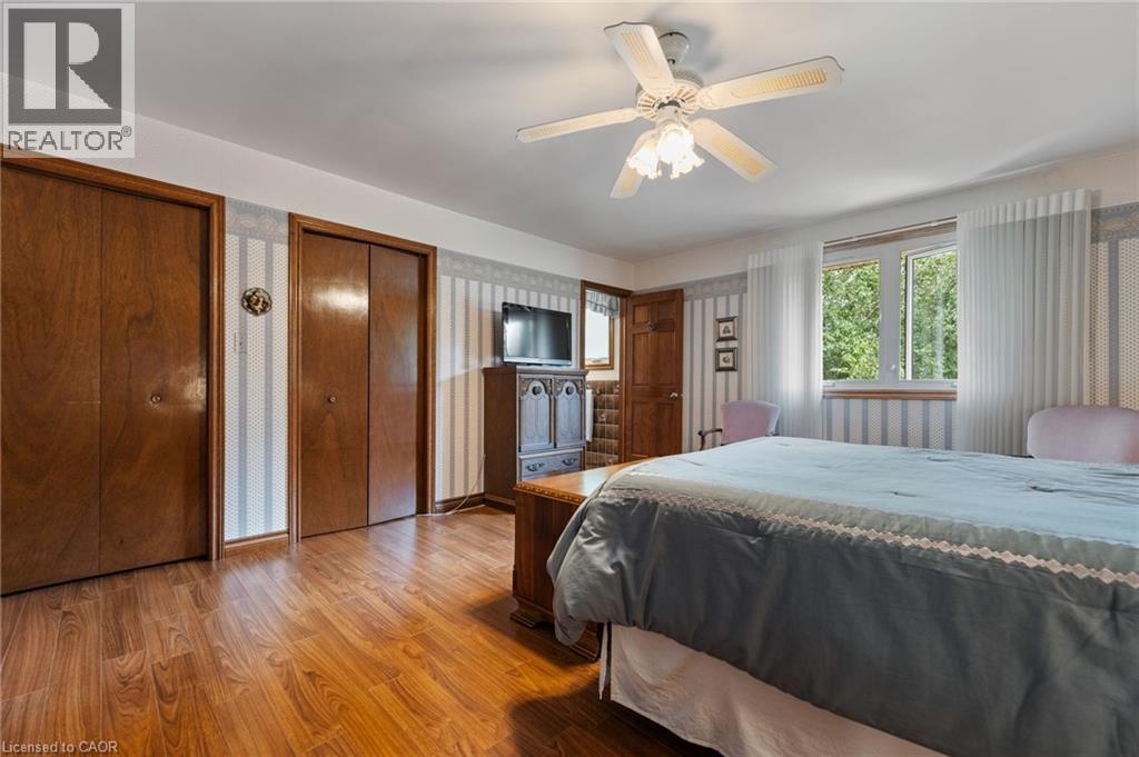 Wood-finish flooring throughout, featuring a ceiling fan with integrated lighting, two built-in bi-fold closets with wood doors, and a double window - 7 Thomson Road, Simcoe, ON - Indoor Photo Showing Bedroom