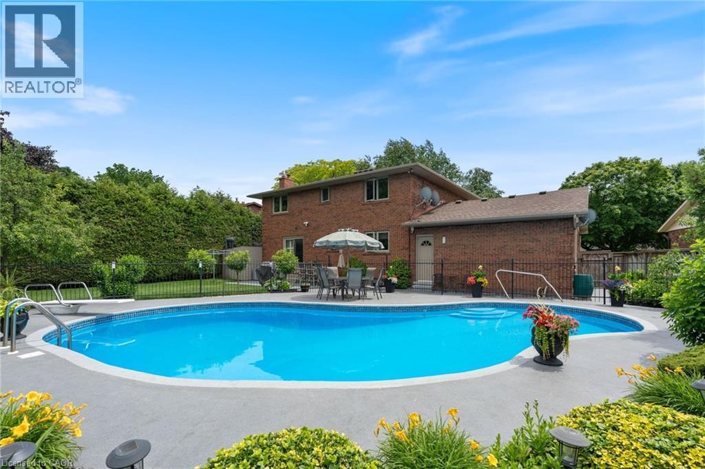 Inground swimming pool featuring an integrated diving board and broad concrete surround - 7 Thomson Road, Simcoe, ON - Outdoor With In Ground Pool With Backyard