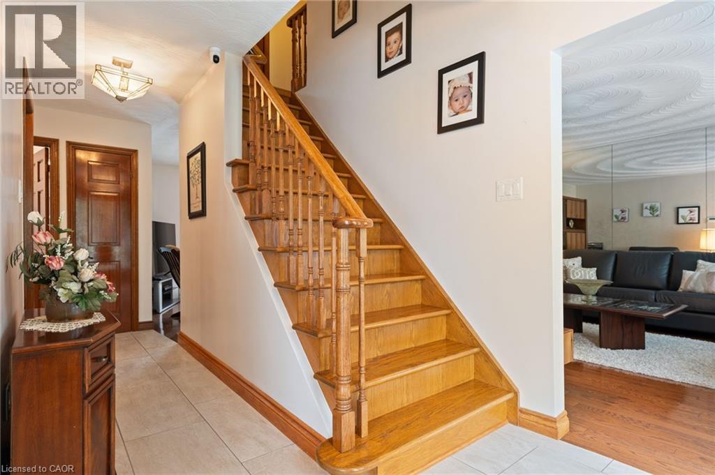 Solid wood staircase with baluster railing, showcasing a paneled wood door and light tile flooring - 7 Thomson Road, Simcoe, ON - Indoor Photo Showing Other Room
