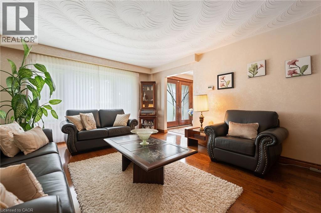 Spacious living area featuring wood-finish flooring, a textured ceiling, and a broad window with vertical blinds - 7 Thomson Road, Simcoe, ON - Indoor Photo Showing Living Room