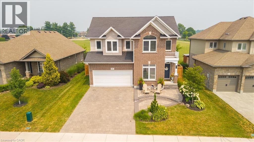 Brick and siding exterior featuring a two-car garage, arched window, and a paver stone driveway - 87 Boyd Boulevard, Thamesford, ON - Outdoor With Facade
