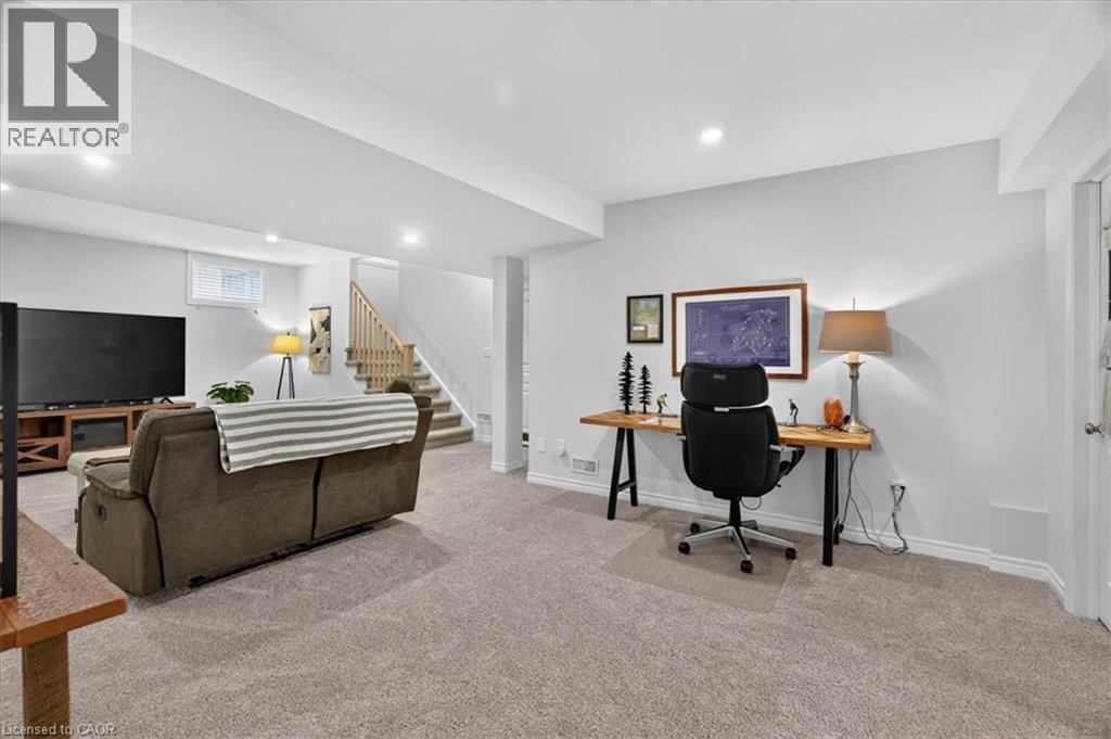 Carpeted lower level featuring recessed lighting, light gray walls, a window, a staircase with wood railings, and a built-in desk area - 87 Boyd Boulevard, Thamesford, ON - Indoor
