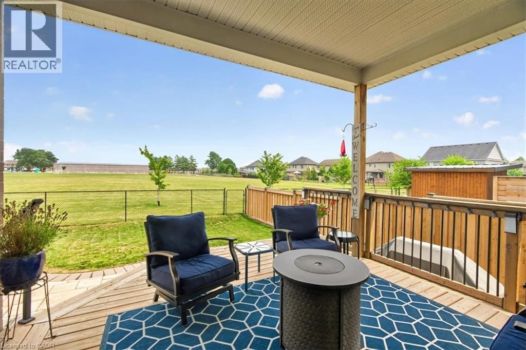 Expansive wooden deck featuring a covered patio, baluster railing, and open green space beyond - 87 Boyd Boulevard, Thamesford, ON - Outdoor With Deck Patio Veranda With Exterior