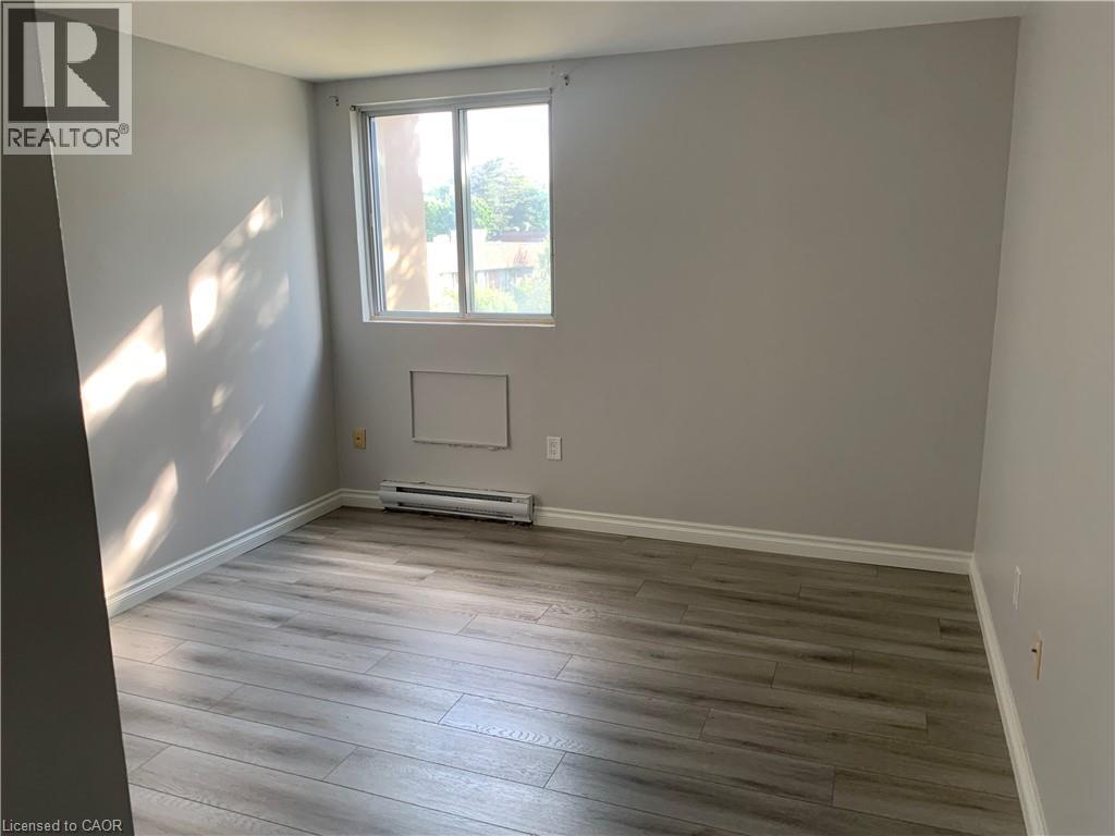 Room featuring a window, light gray walls, and wood-finish flooring - 65 Highland Crescent Unit# 201, Kitchener, ON - Indoor Photo Showing Other Room
