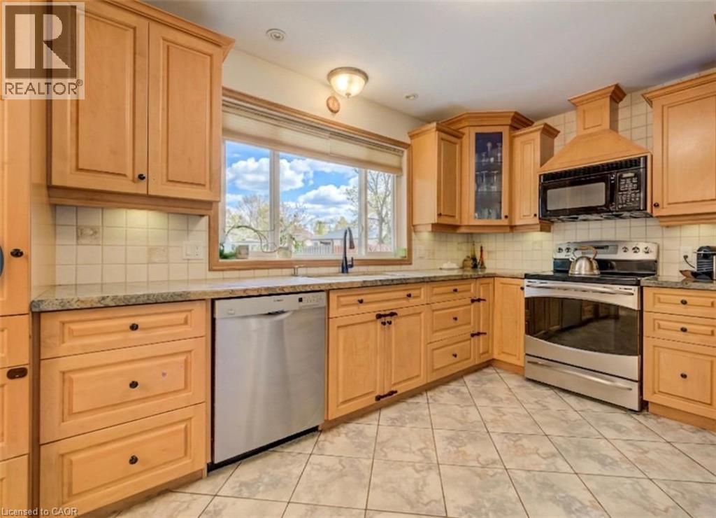Kitchen featuring natural wood-finish cabinetry, light-toned tile flooring, granite-look countertops, and stainless steel appliances including a range, microwave, and dishwasher - 209 Willowdale Avenue Unit# Upper, Waterloo, ON - Indoor Photo Showing Kitchen