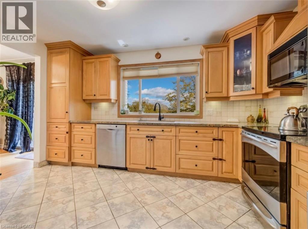Kitchen featuring light wood cabinetry with varied storage options, stainless steel appliances including a dishwasher and range, granite-look countertops, and a tiled backsplash - 209 Willowdale Avenue Unit# Upper, Waterloo, ON - Indoor Photo Showing Kitchen