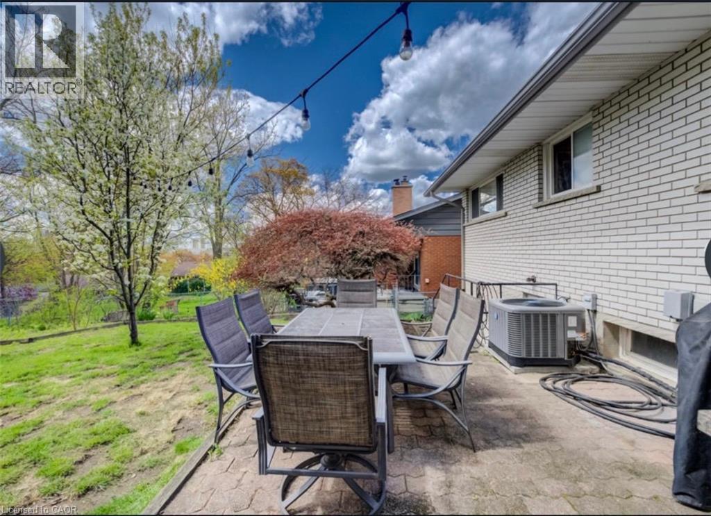 Expansive patio area featuring a textured concrete surface and direct access to a sloped grassy yard - 209 Willowdale Avenue Unit# Upper, Waterloo, ON - Outdoor With Deck Patio Veranda With Exterior