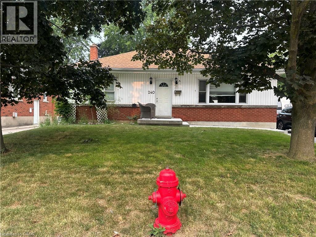 Single-story residence featuring white siding, a contrasting red brick foundation, and a light-toned shingled roof - 240 West 2Nd Street, Hamilton, ON - Outdoor