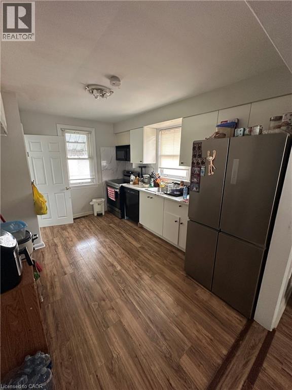 Kitchen featuring wood-finish flooring, white cabinetry, and stainless-steel appliances - 240 West 2Nd Street, Hamilton, ON - Indoor