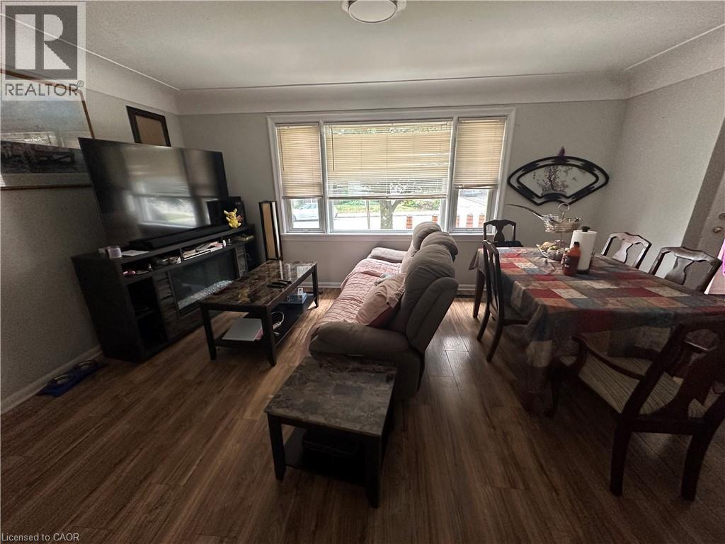 Open concept living and dining area featuring wood-finish flooring, white trim, and a rectangular window with blinds - 240 West 2Nd Street, Hamilton, ON - Indoor Photo Showing Living Room