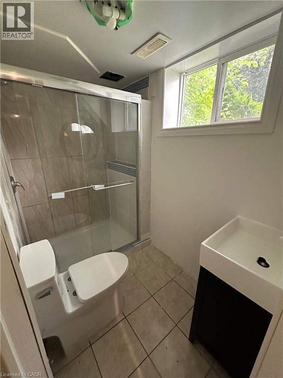 Bathroom featuring a glass-enclosed shower with tile surround, a low-profile toilet, and a modern vanity with integrated sink - 240 West 2Nd Street, Hamilton, ON - Indoor Photo Showing Bathroom