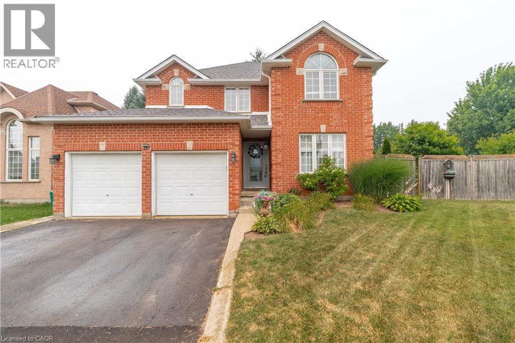 Brick exterior featuring a two-car garage, asphalt driveway, front entry with transom window, landscaped garden beds, and a grasse dfront yard - 79 Beaverbrook Crescent, Cambridge, ON - Outdoor With Facade