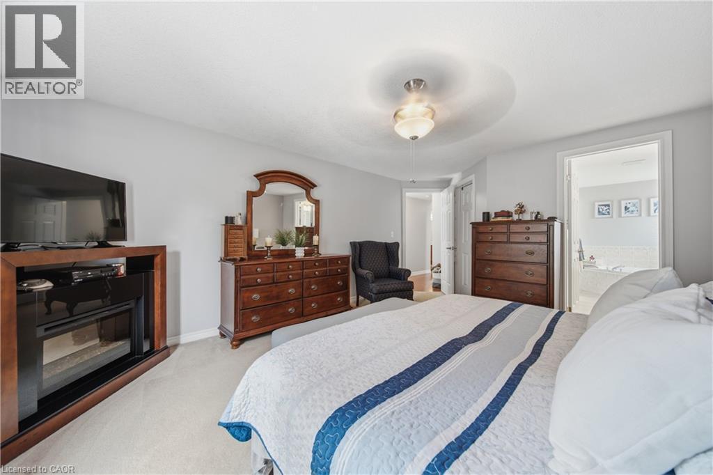 Carpeted bedroom featuring a built-in electric fireplace and a ceiling-mounted fixture - 79 Beaverbrook Crescent, Cambridge, ON - Indoor Photo Showing Bedroom