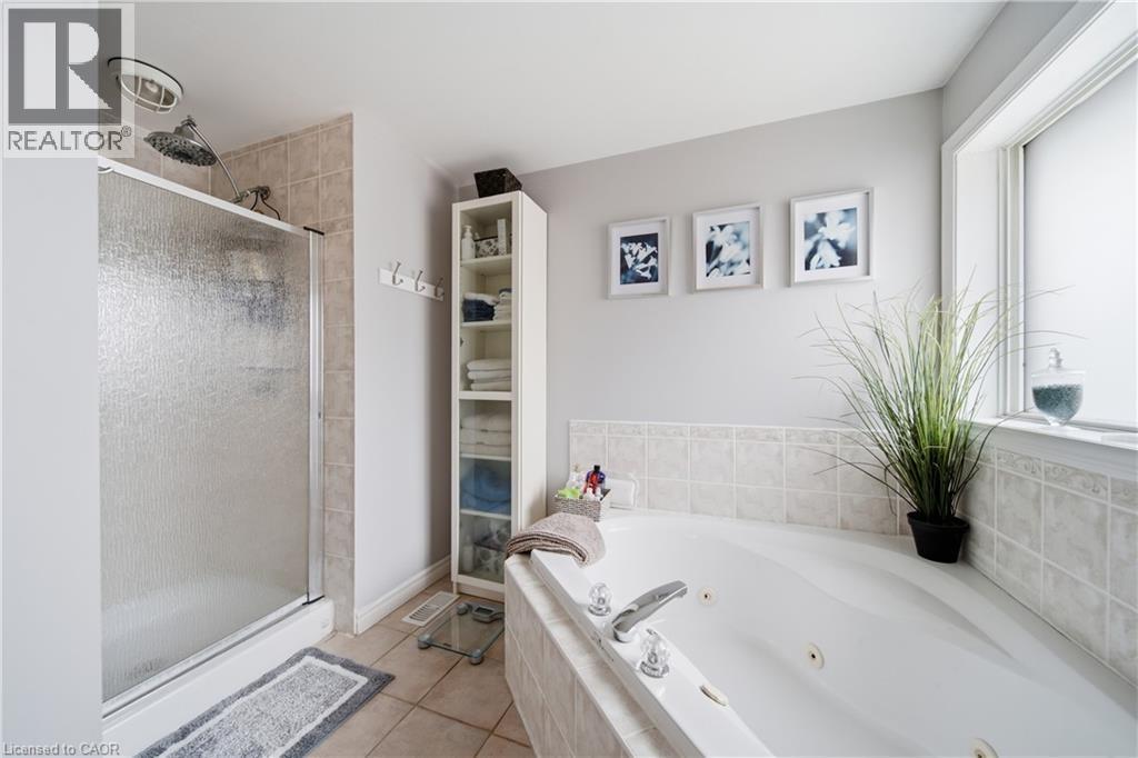Bathroom with a white jetted tub, ceramic tile surround, and a clear glass shower enclosure - 79 Beaverbrook Crescent, Cambridge, ON - Indoor Photo Showing Bathroom