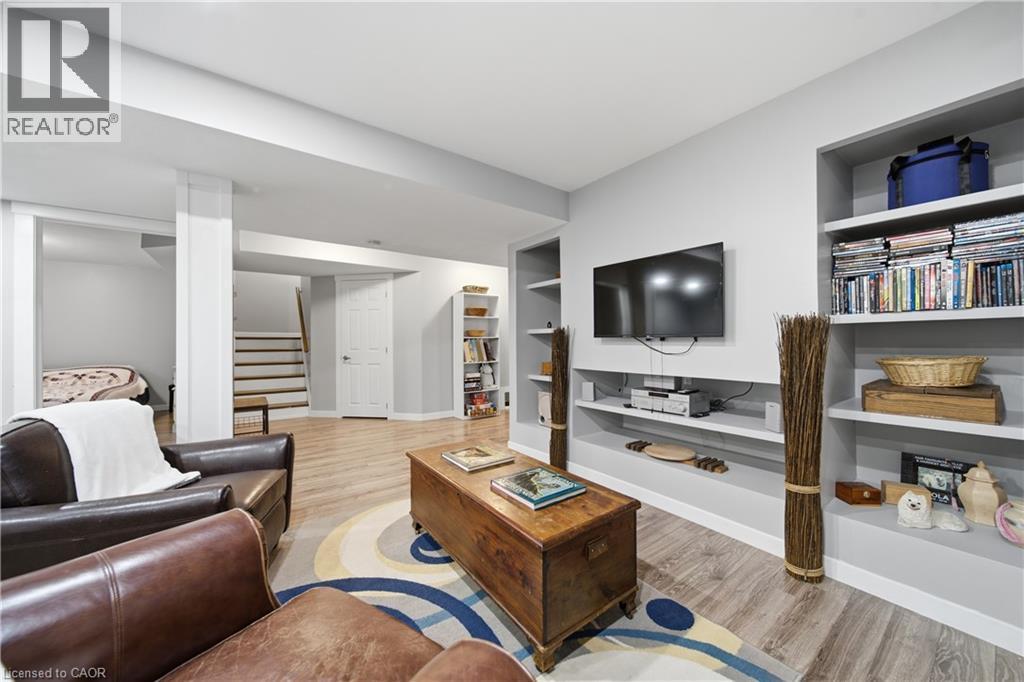 Spacious living area featuring light wood-finish flooring, built-in shelving, a dedicated media wall, and a separate stairway access - 79 Beaverbrook Crescent, Cambridge, ON - Indoor Photo Showing Living Room