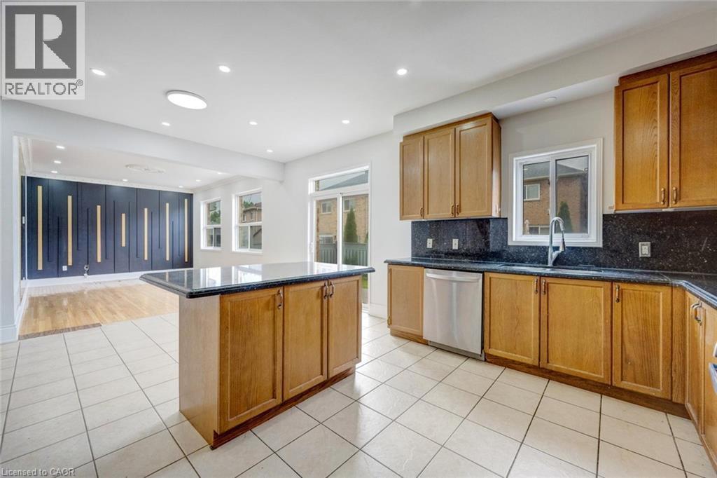 Kitchen featuring wood cabinetry, dark stone countertops, stainless steel dishwasher, and a center island - 5 Freshspring Drive, Brampton, ON - Indoor Photo Showing Kitchen