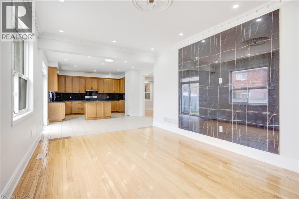 Hardwood flooring throughout the main living area, leading to a kitchen with wood cabinetry and black countertops - 5 Freshspring Drive, Brampton, ON - Indoor Photo Showing Other Room