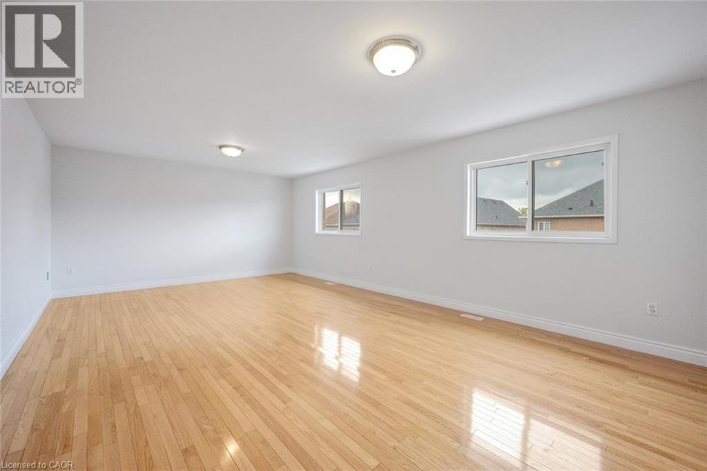 Spacious room featuring wood-finish flooring, two windows with white frames, and two ceiling-mounted dome light fixtures - 5 Freshspring Drive, Brampton, ON - Indoor Photo Showing Other Room