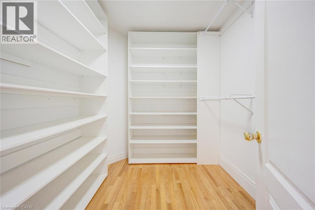 Walk-in closet featuring light wood-finish flooring, white built-in shelving, white walls, and a white interior door with a brass-finish doorknob - 5 Freshspring Drive, Brampton, ON - Indoor